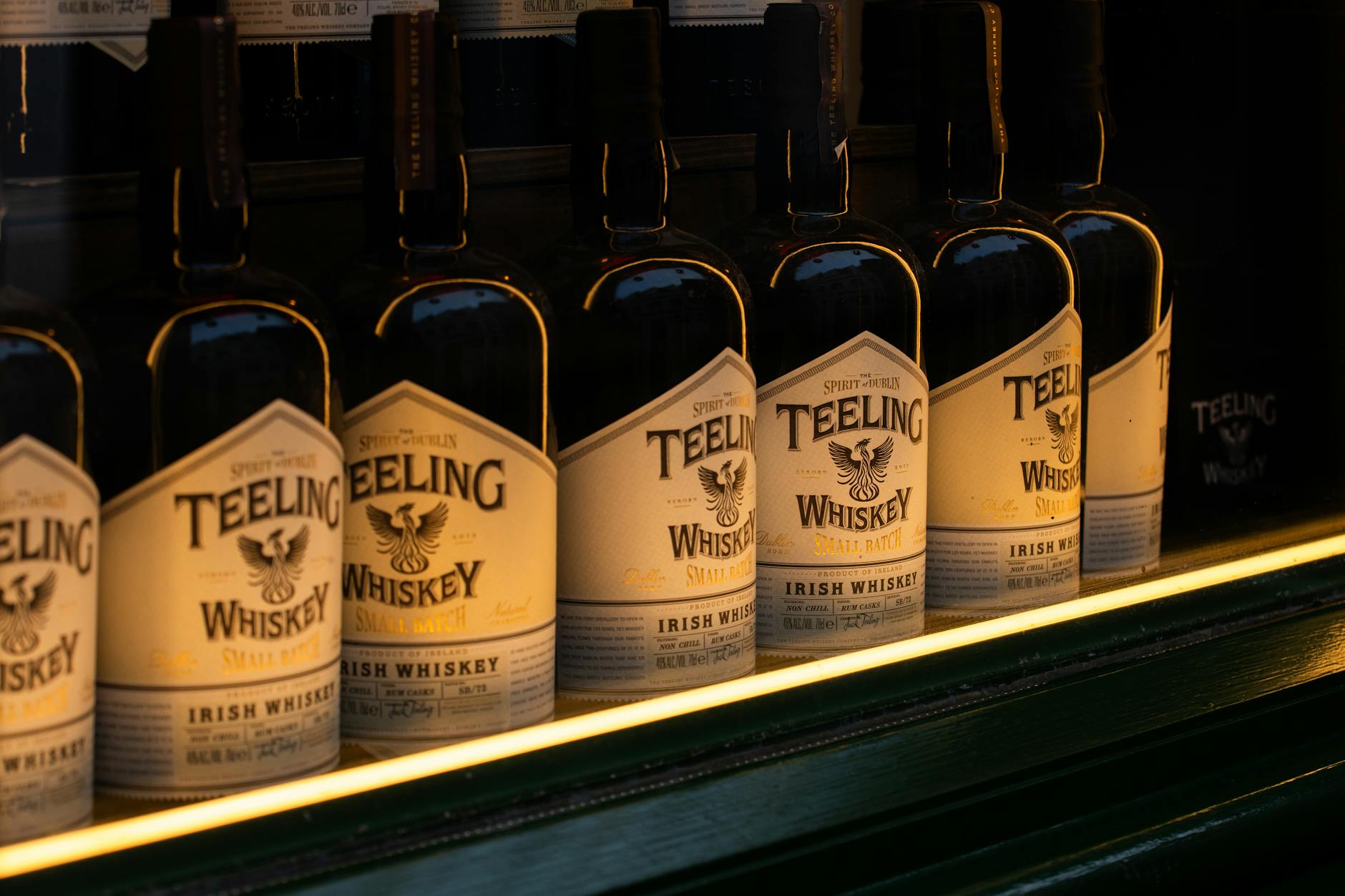 Butelki irlandzkiej whisky Teeling ustawione w rzędzie w złotym świetle