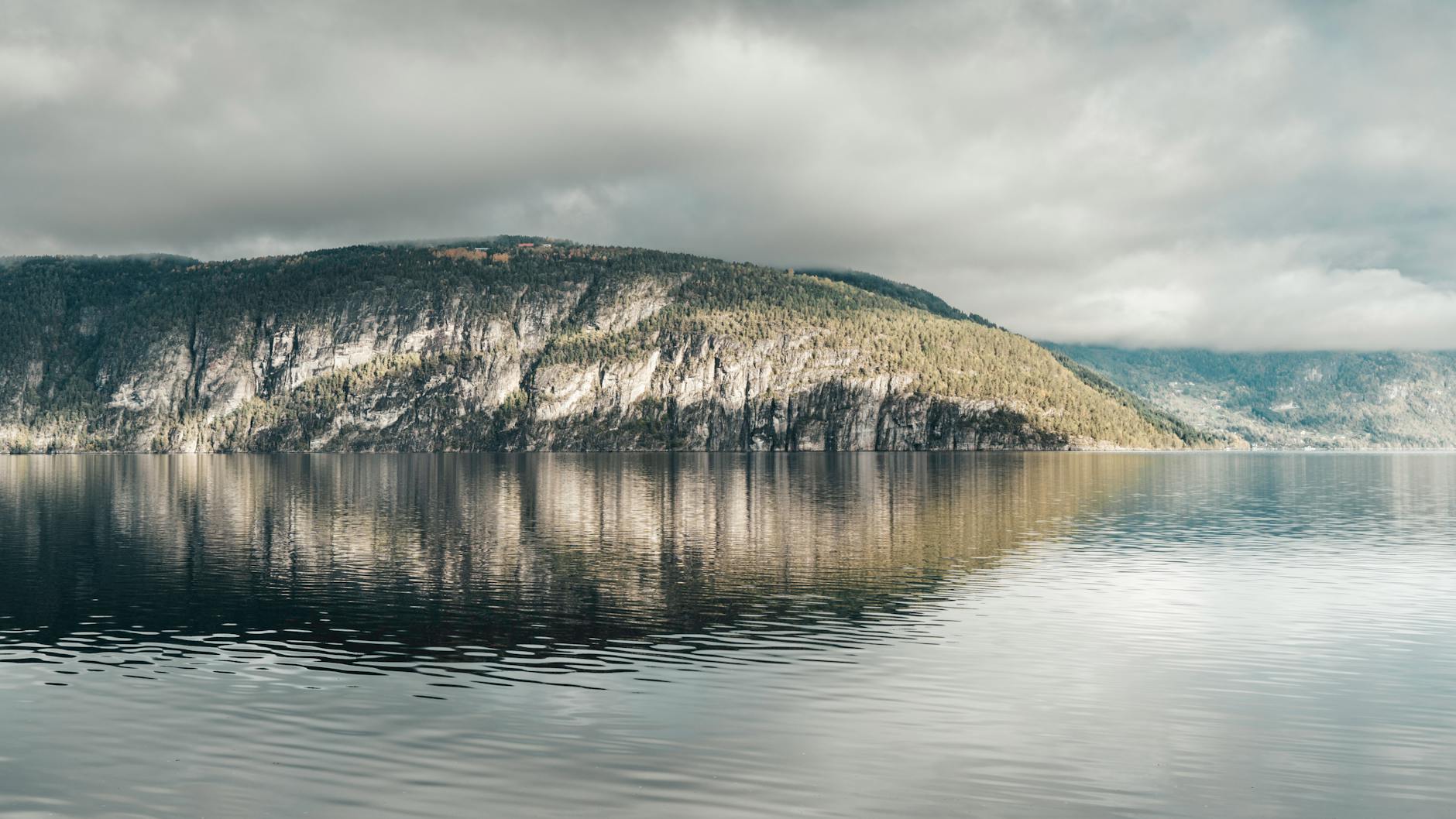 Norweski fiord o świcie z odbiciem stromych klifów w spokojnej wodzie