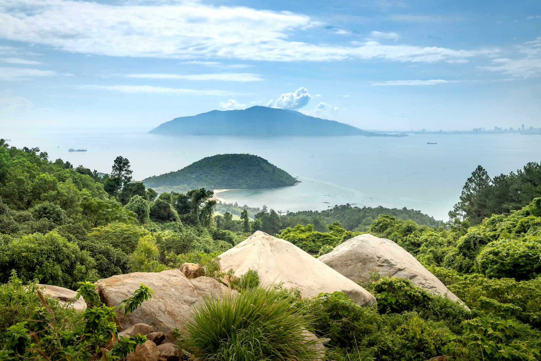 Zielone zbocze z głazami nad spokojnym morzem i odległą wyspą
