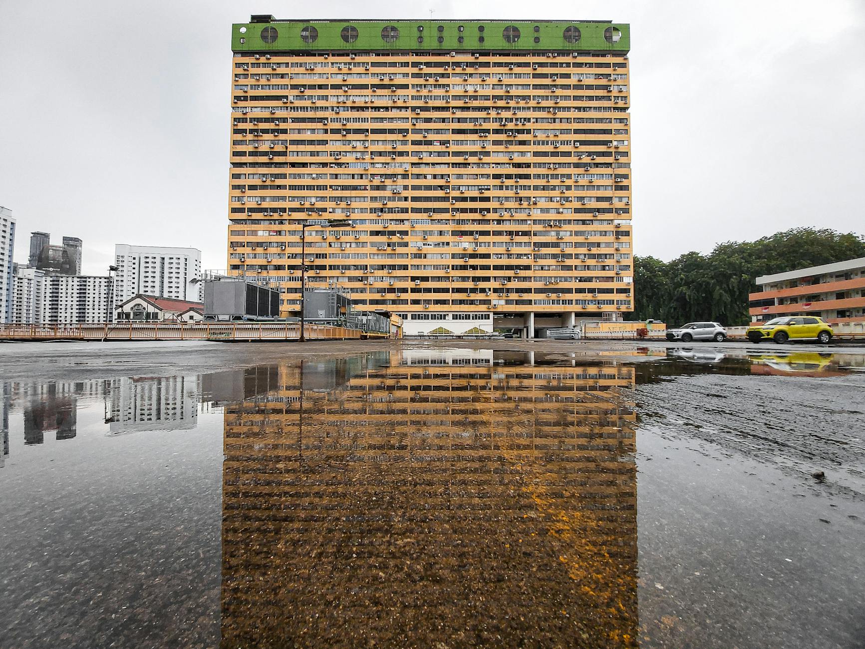 Żółty budynek w Singapurze odbijający się w kałuży po deszczu