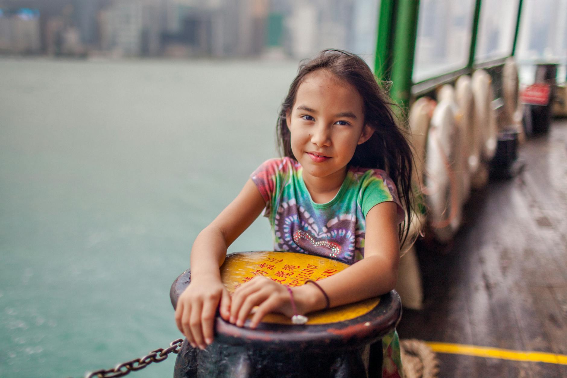 Dziewczynka na promie z panoramą wieżowców Hongkongu w tle