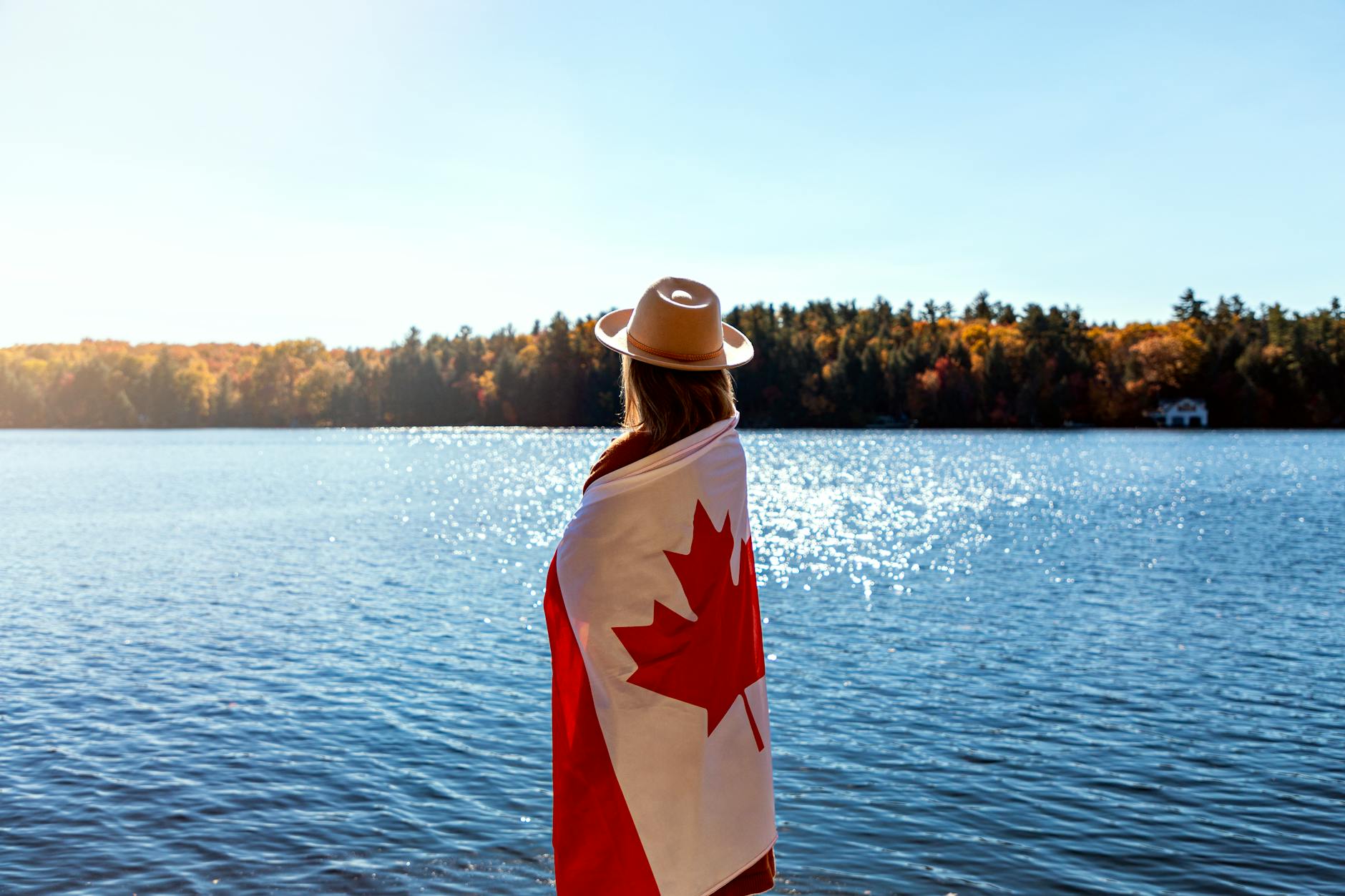 Kobieta w kanadyjskiej fladze nad jesiennym jeziorem w Ontario