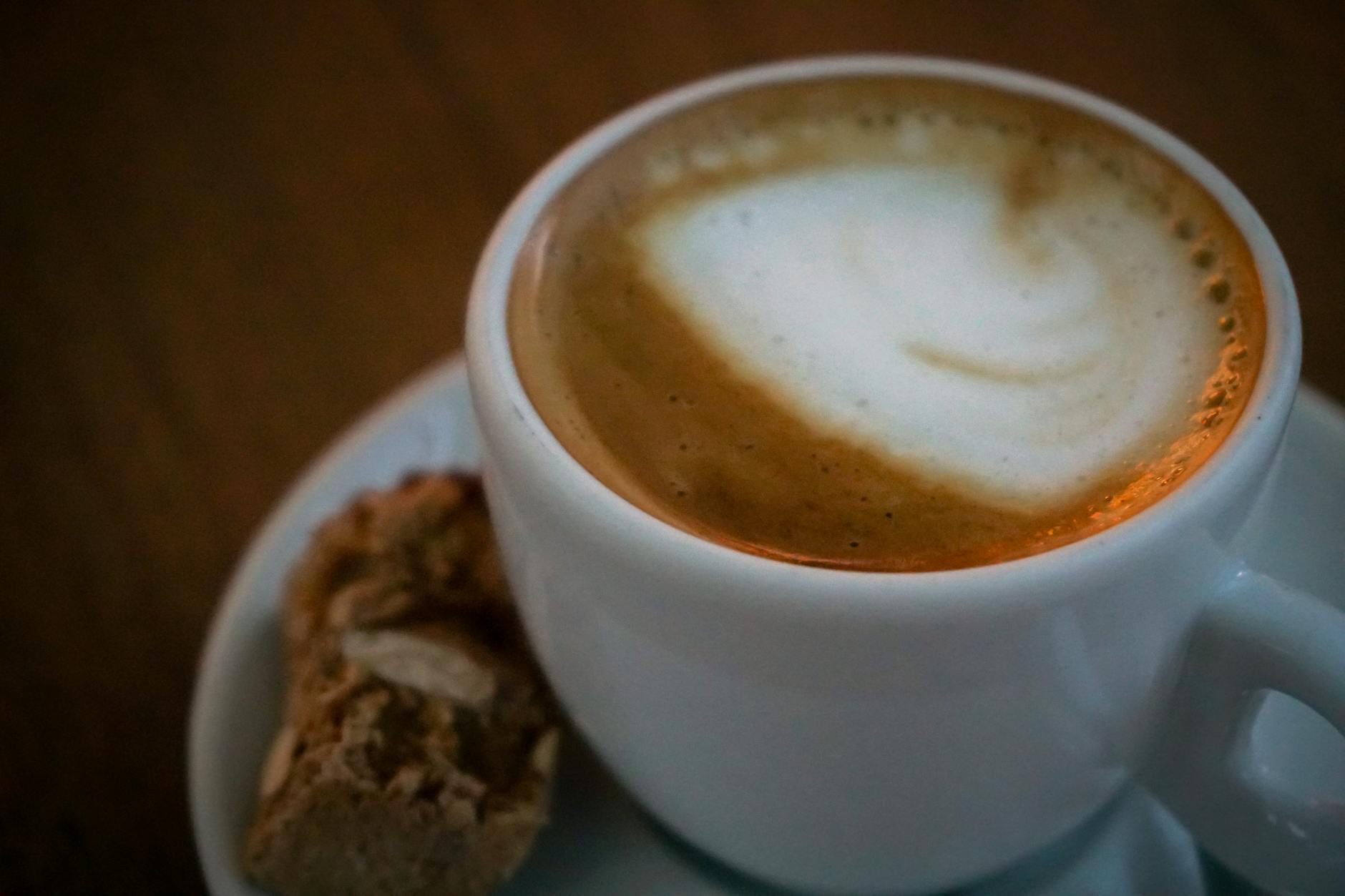 Porcelanowa filiżanka cappuccino z biscotti na spodku, włoskie śniadanie