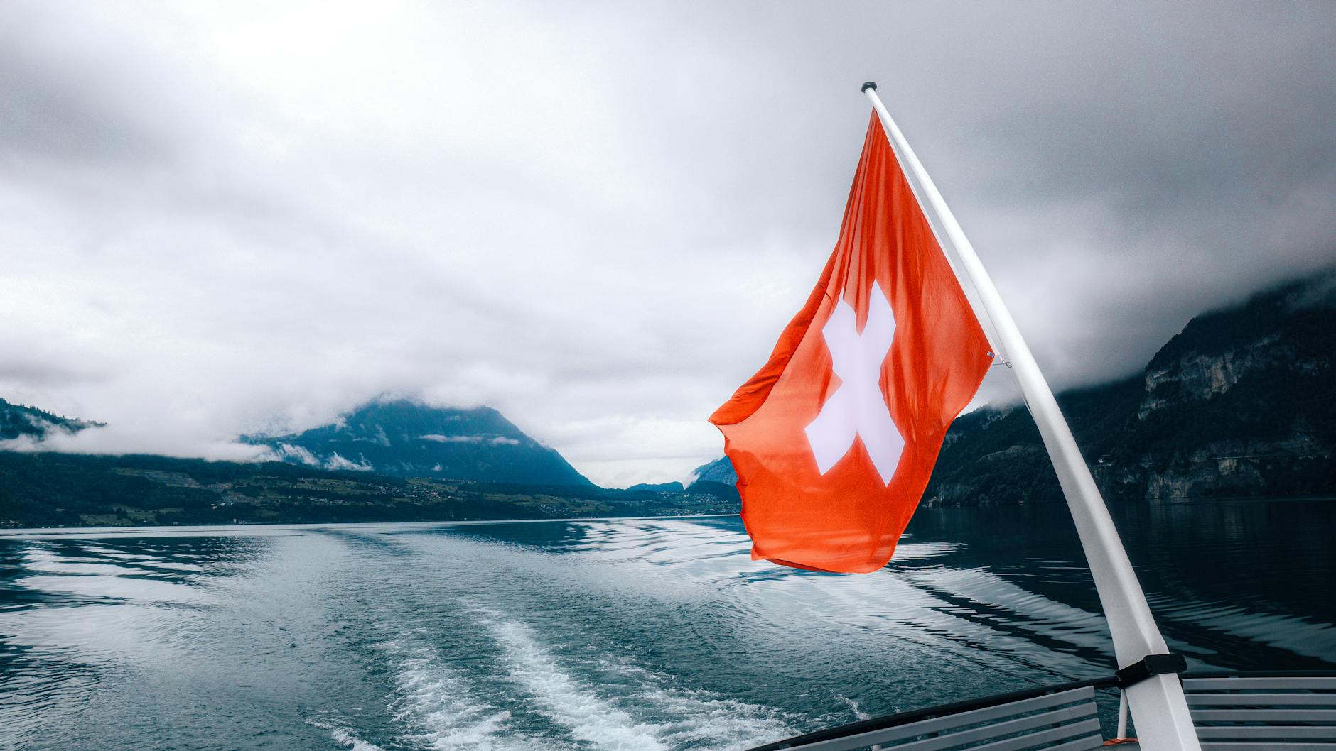Rejs łodzią po szwajcarskim jeziorze z flagą na tle gór